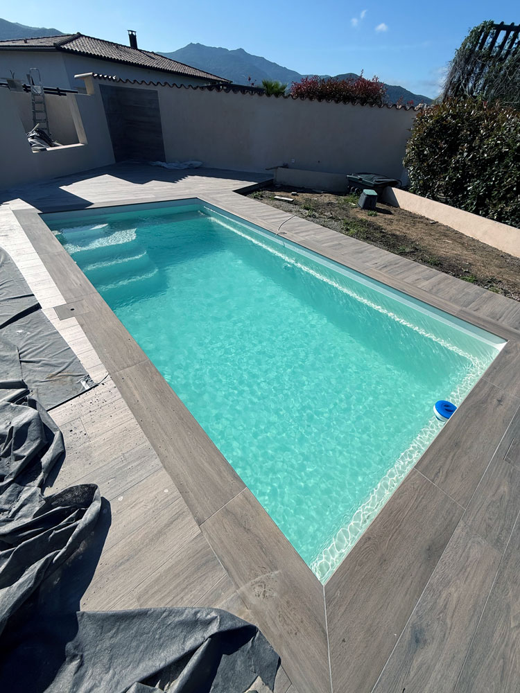 Piscine coque Star 6 beige en Corse avec terrasse carrelée imitation bois — Mapico